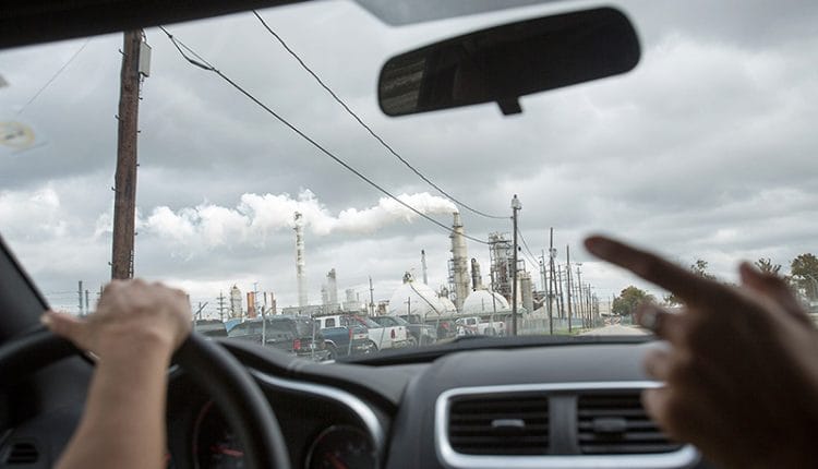 Photo of a polluting oil refinery through the windshield of a car leading a 