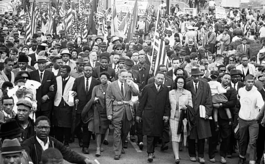 John Lewis (second from left in the main group, wearing white tunic), Dr.  Martin Luther King (center) and other civil rights activists arrive in Montgomery, Alabama, after marching from Selma in non-violent protest on March 25, 1965