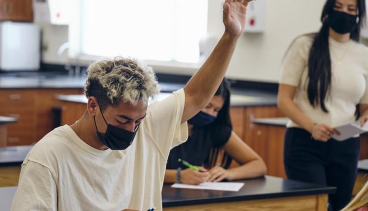 High school teacher and student in classroom wear protective face mask