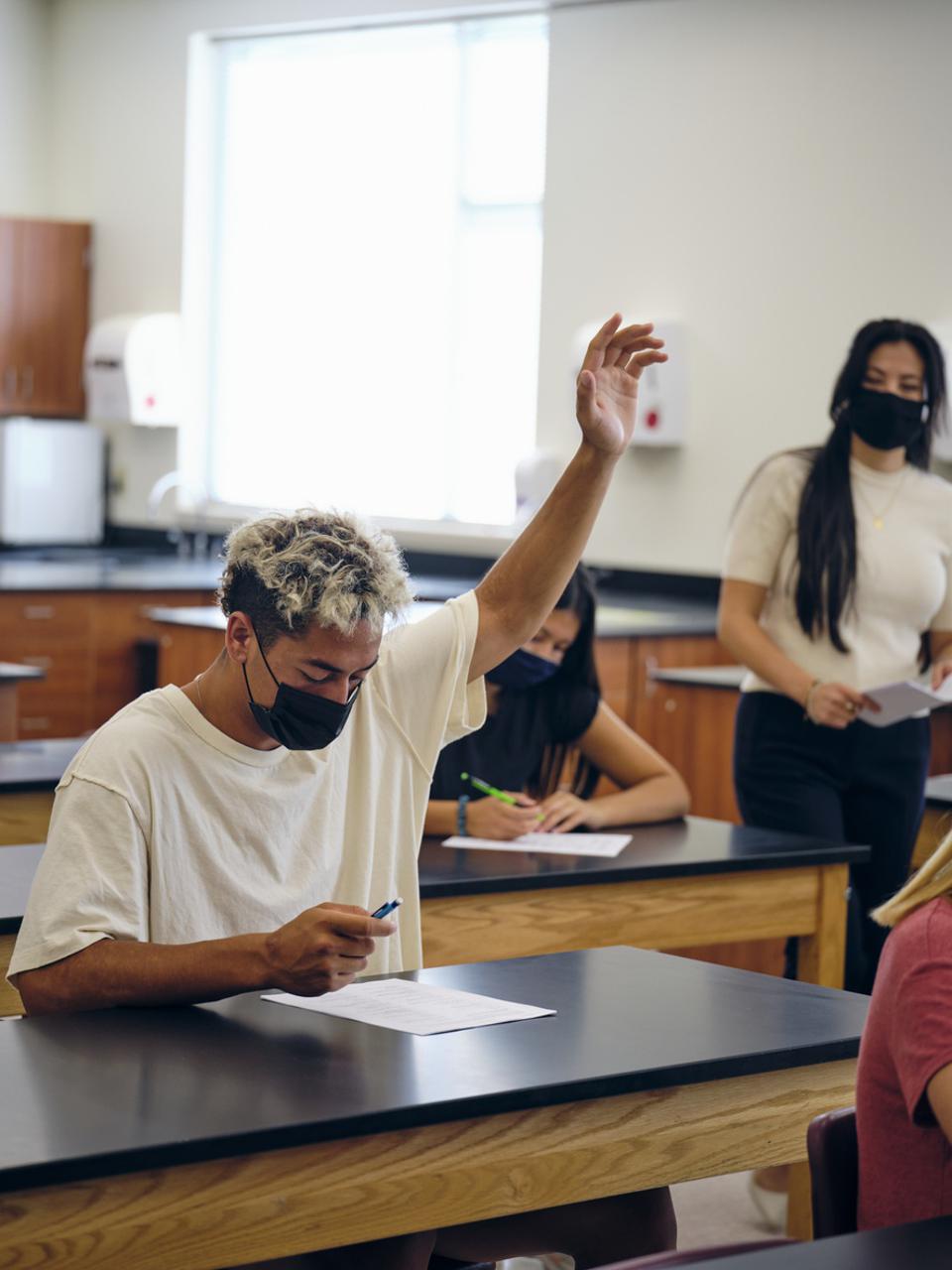 High school teacher and student in classroom wear protective face mask