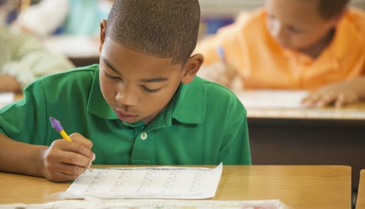 A black boy is working on a math problem in class.