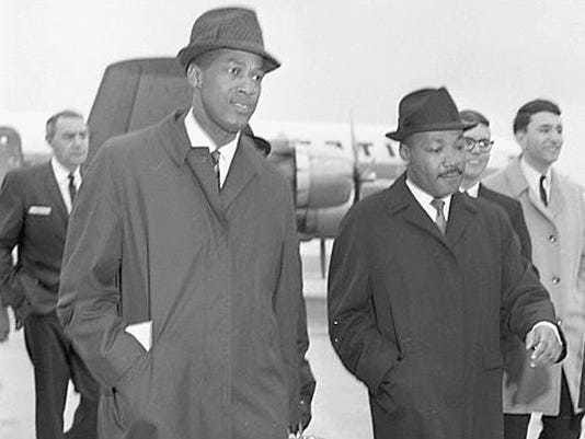 Dr.  Martin Luther King Jr. arrives at Lansing Airport on February 11, 1965.  He is accompanied here by MSU education professor Robert Green (left).  King spoke to Michigan State University students.  Lansing State Journal file photo